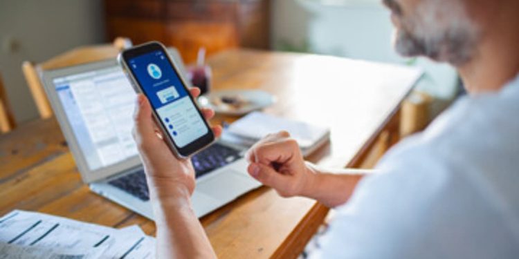 "Investidor acompanhando o saldo de sua conta internacional através de um dispositivo móvel em ambiente doméstico